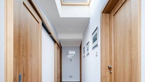 Un estrecho pasillo con puertas de madera y un tragaluz.