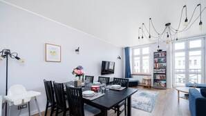 Una sala moderna con comedor, una estantería y un televisor.
