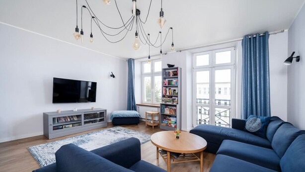 Una sala de estar moderna con un televisor de pantalla plana grande, una estantería, una mesa de centro y un conjunto de sofás.