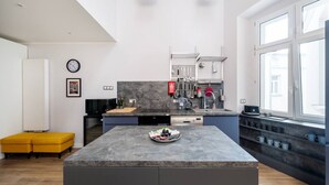 Una cocina moderna con una isla central, electrodomésticos integrados y abundante luz natural gracias a amplios ventanales.