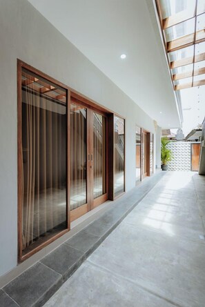 Un pasillo con puertas correderas de vidrio, piso de baldosas y un techo con tragaluces.