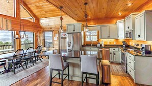 A spacious kitchen with wooden ceilings, a central island, and a dining area with chairs.
