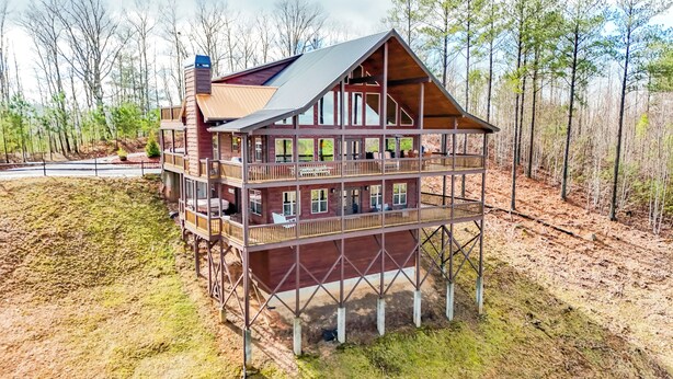 A multi-story wooden cabin with a balcony on each floor, surrounded by trees.