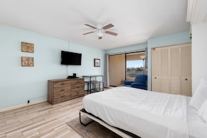 A bedroom with a bed, a desk, a chair, a TV, and a wardrobe.