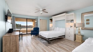 Ein Schlafzimmer mit Bett, Schreibtisch, Stuhl, Deckenventilator und Fenster mit Blick.