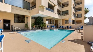 Ein Swimmingpool mit blauem Wasser, umgeben von beigen Wänden und Balkonen.