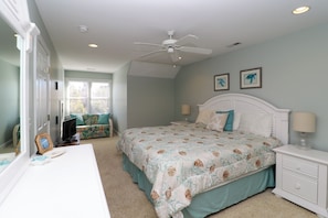 A bedroom with a bed, nightstands, a dresser, a ceiling fan, and two framed pictures on the wall.