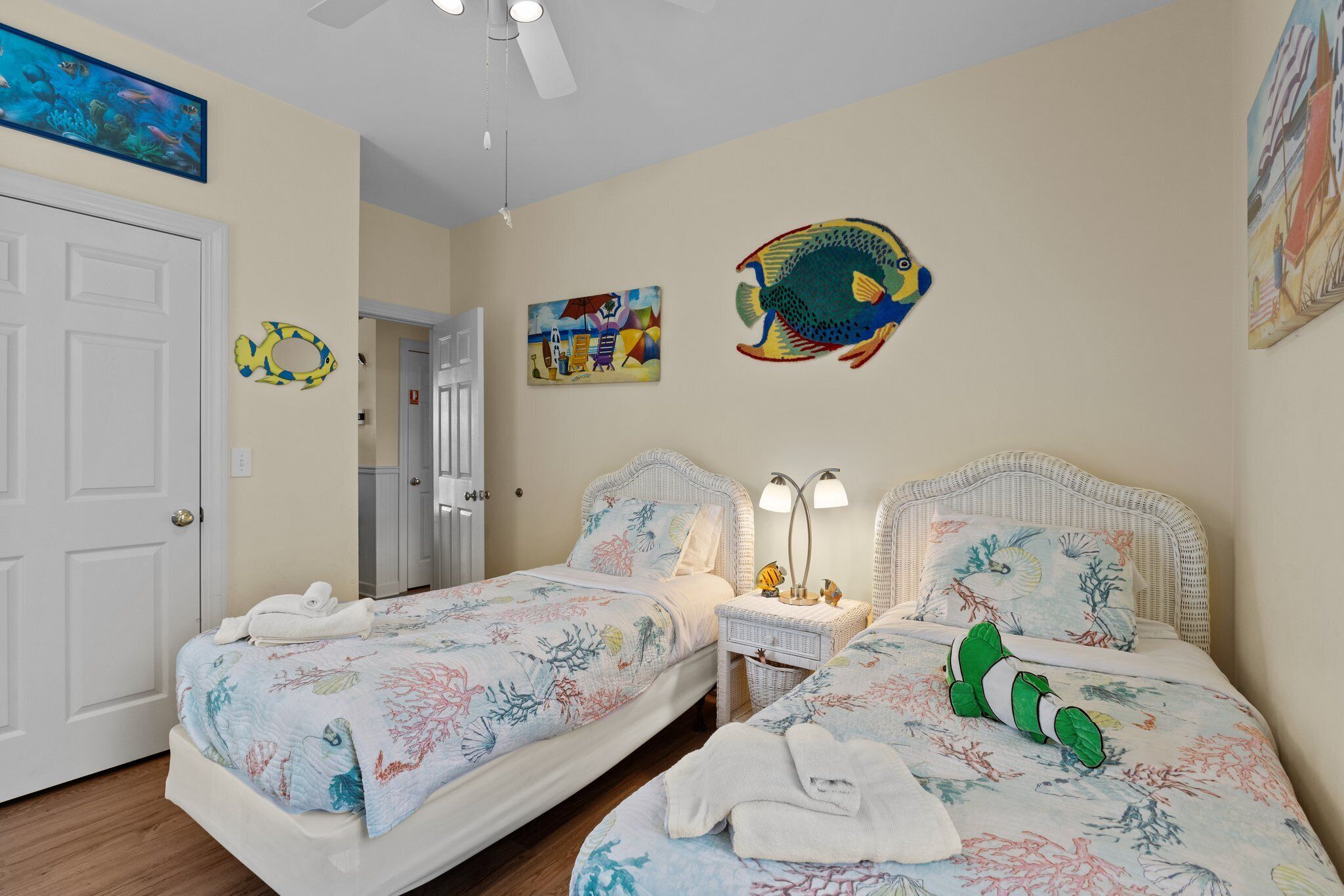 A bedroom with two beds, a ceiling fan, and wall art.
