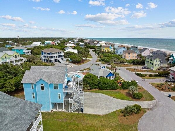 A coastal residential area with houses, a beach, and a clear sky.
