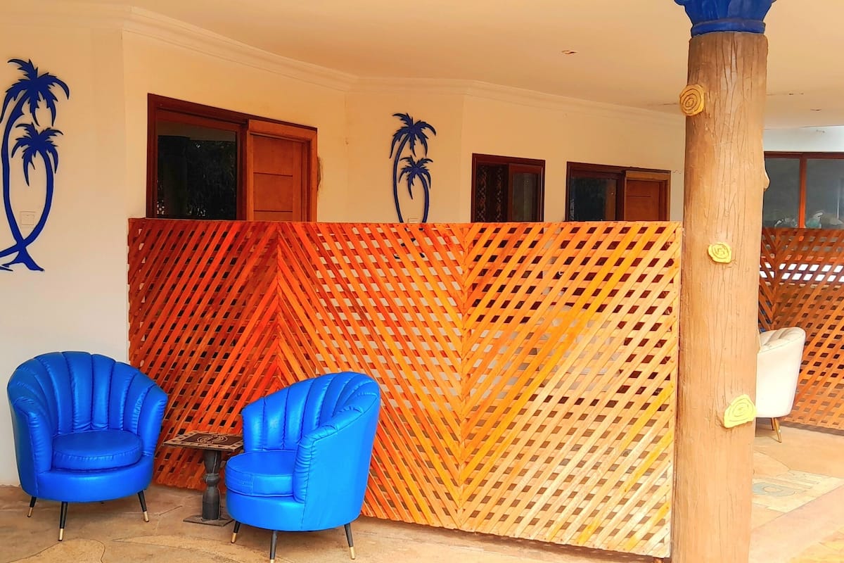 A room with two blue armchairs, a small table, and a wooden partition with a lattice design.