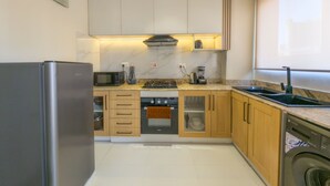 A modern kitchen with a refrigerator, microwave, stove, oven, and dishwasher. - Glassvine - 1D (Lagos)