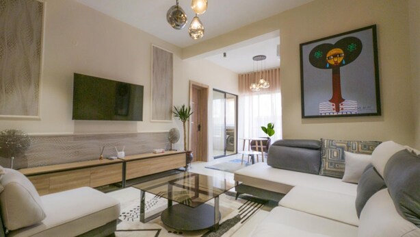 A modern living room with a sofa set, a coffee table, and a TV mounted on the wall. - Glassvine - 1D (Lagos)