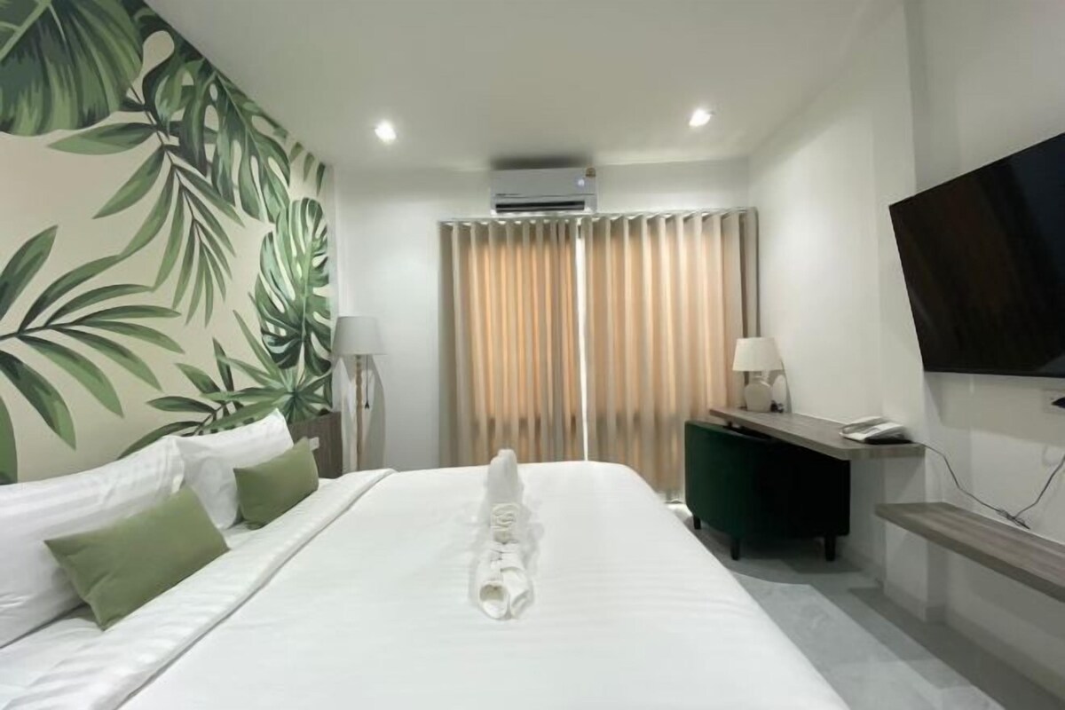 Hotelkamer met een bed, bureau, stoel, televisie en raam met gordijnen.