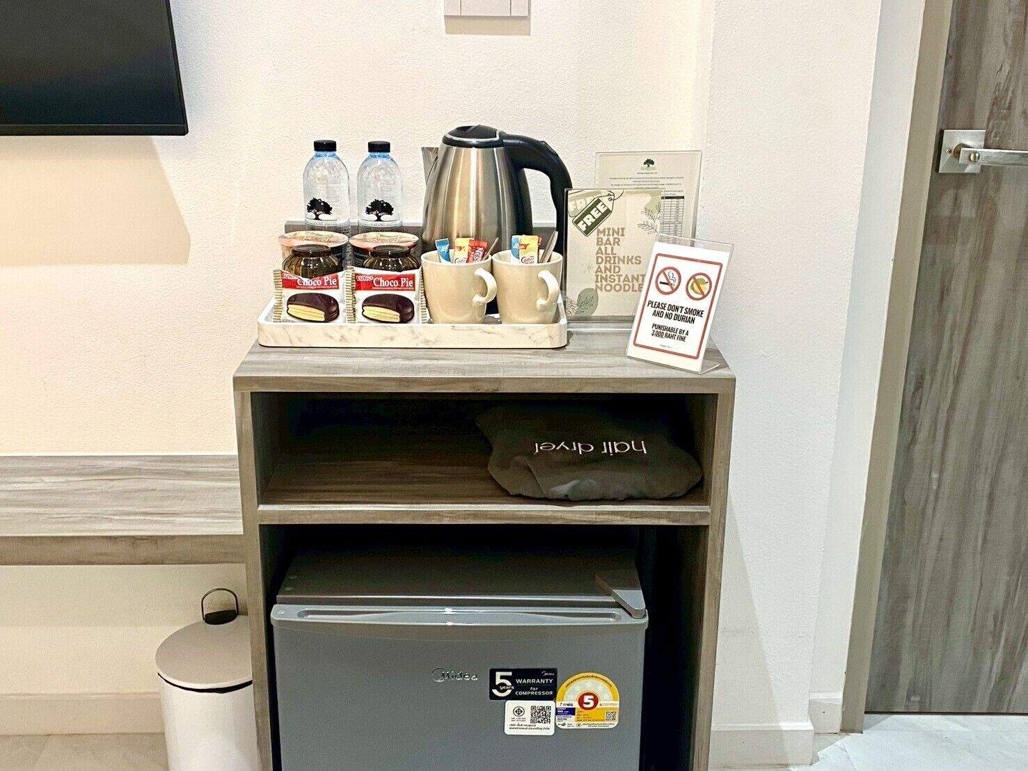 Un mini-bar équipé d’une machine à café, de bouteilles d’eau, de collations et d’un panneau indiquant qu’il est interdit de fumer.