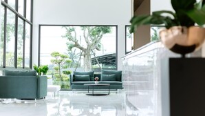 A modern living room with a sofa, a coffee table, and a potted plant. - Tree Airport Hotel Hatyai (Khuan Lang)