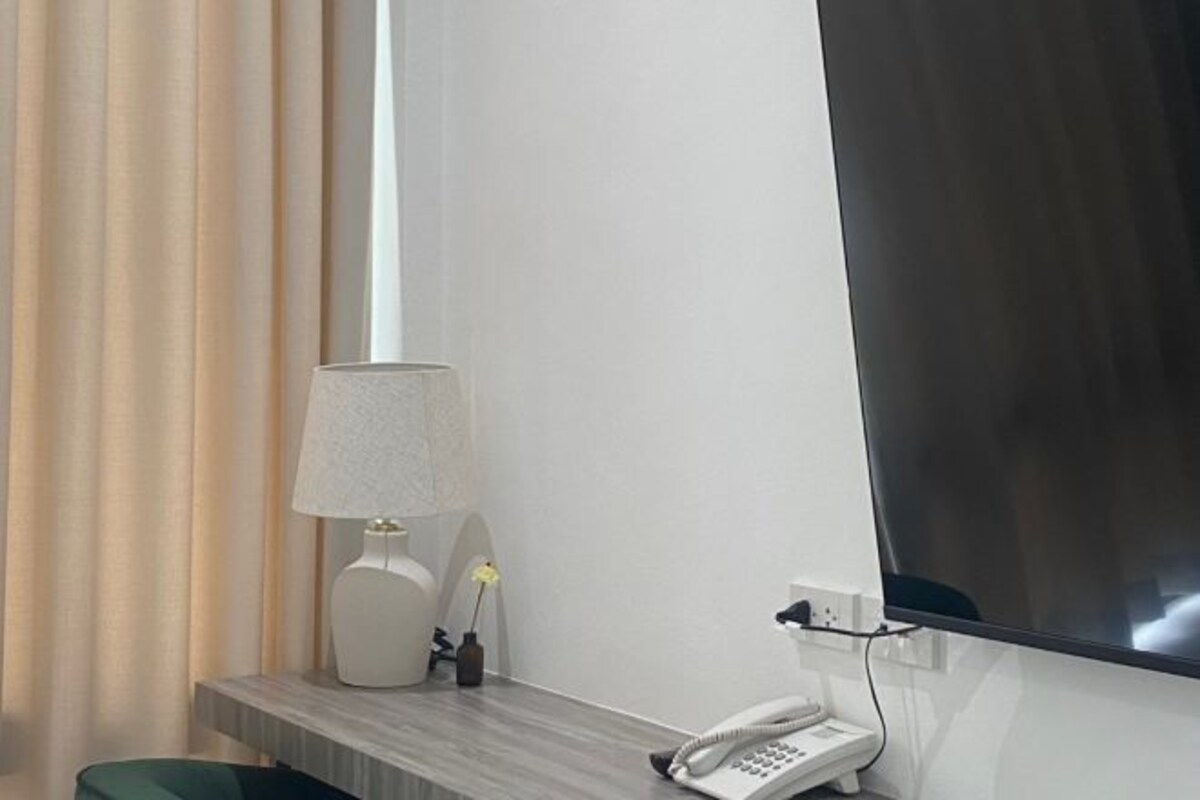 Een hotelkamer met een bureau, lamp, telefoon en een grote spiegel.