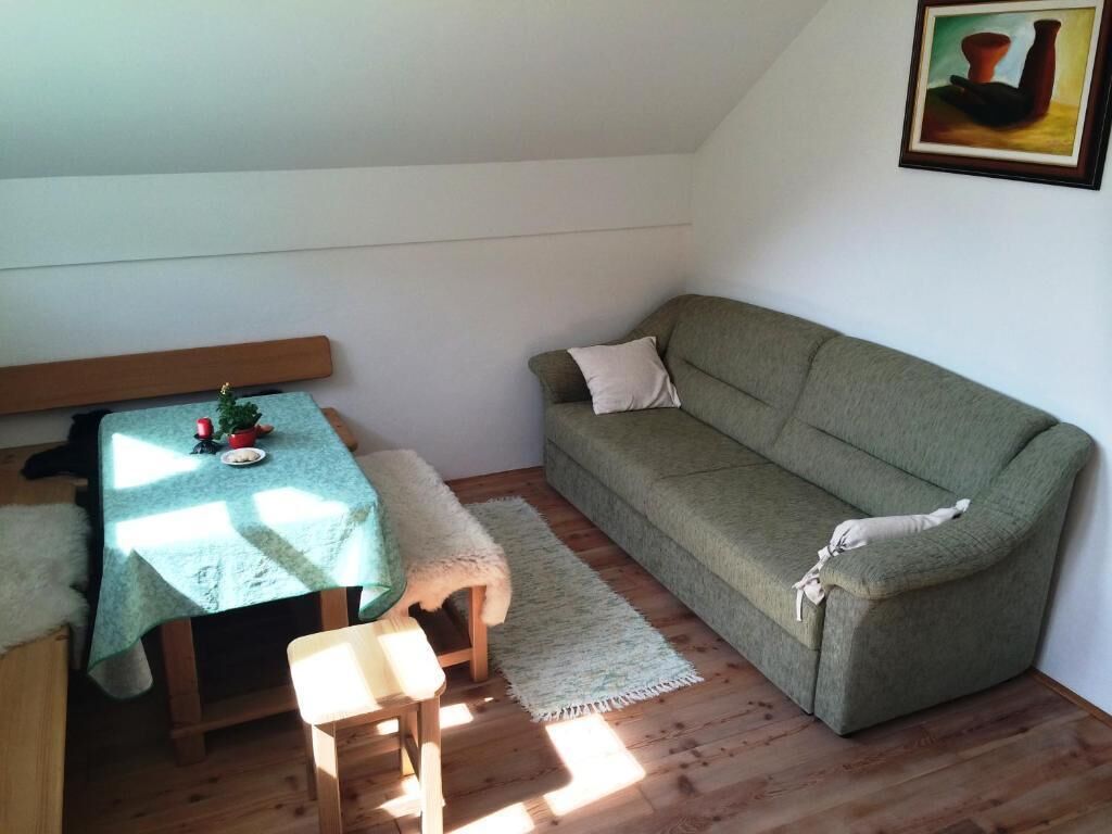 Una habitación acogedora con un sofá verde, una mesita con mantel verde y un banco.