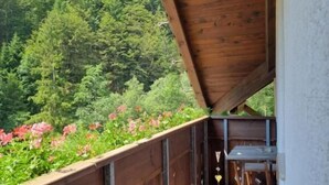 Un balcón de madera con vista a un área boscosa y flores.