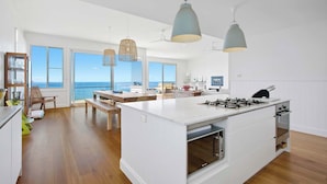 A spacious kitchen with a large island, pendant lights, and a view of the ocean. - Fairwinds Manyana Stunning Views (Manyana)
