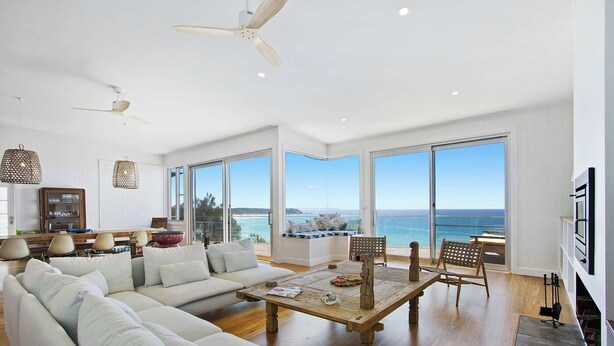 A spacious living room with a large sofa, a wooden coffee table, and a view of the ocean through large windows. - Fairwinds Manyana Stunning Views (Manyana)