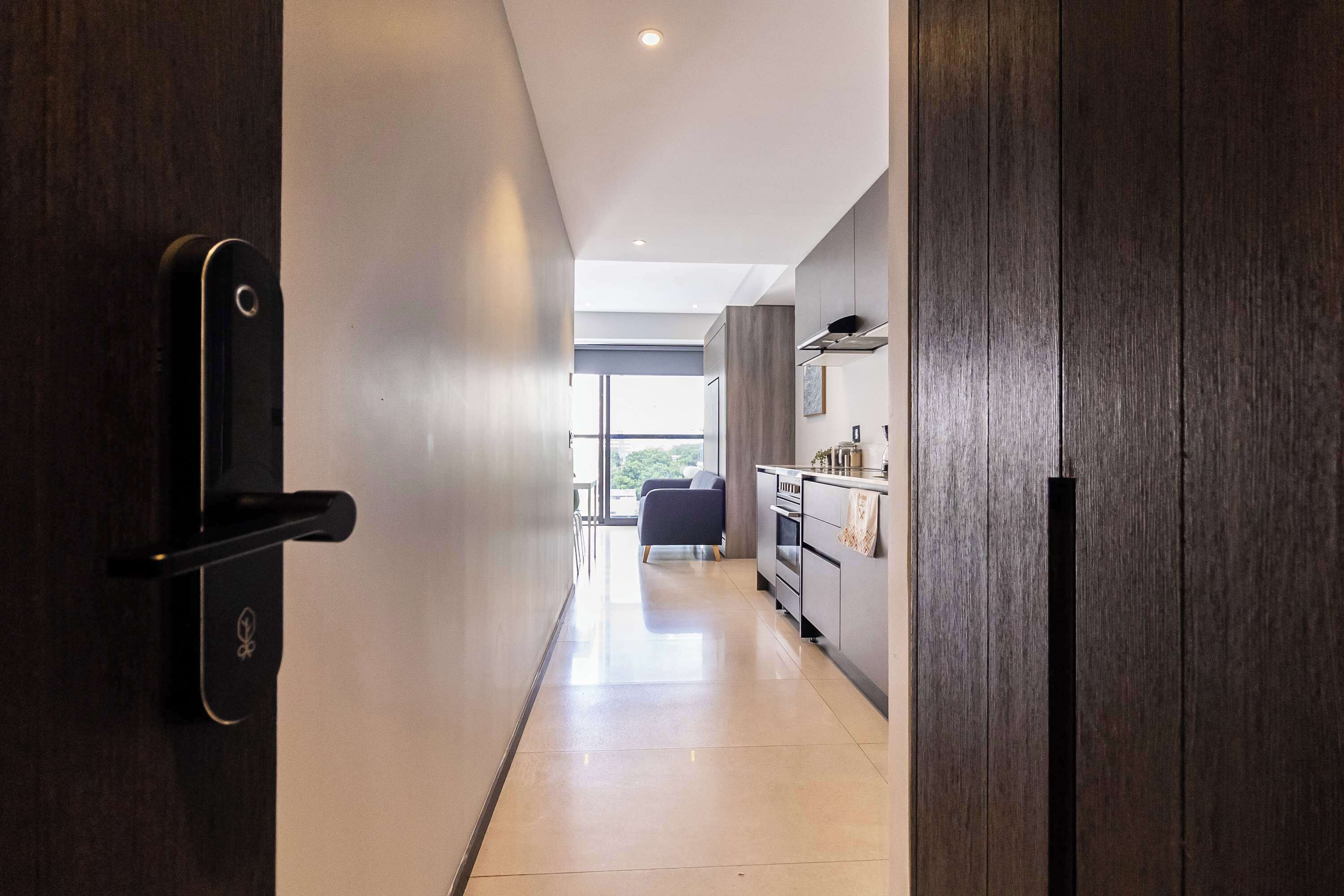 A modern kitchen with dark wood cabinets, a stainless steel range hood, and a large window providing natural light.
