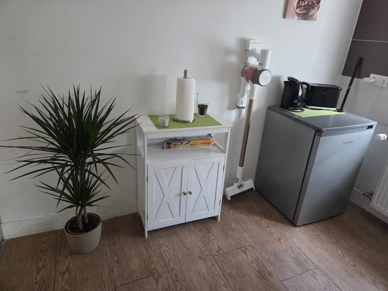 A kitchenette with a refrigerator, a microwave, a coffee maker, and a potted plant.