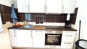Een keuken met witte kastjes, een fornuis, een oven, een spoelbak en een koffiezetapparaat.