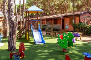 A playground with a slide, swings, and a climbing structure. - Il Gabbiano Maremma Superior Cottage 4 PAX (Grosseto)
