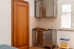 Une cuisine de taille réduite, dotée d’une porte en bois, de placards en acier inoxydable, d’un petit évier et d’une fenêtre.