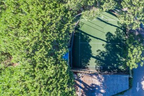 Vue aérienne d’un court de tennis entouré d’une végétation luxuriante.