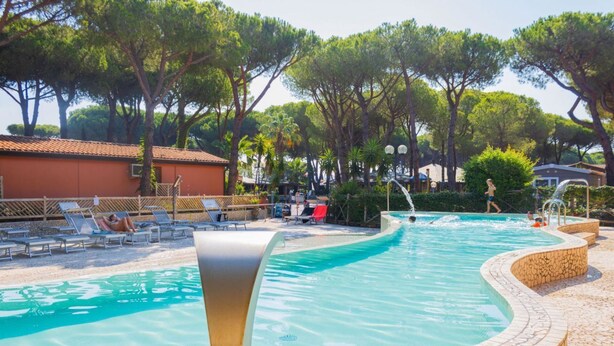 En swimmingpool med liggestole og en fliseterrasse.