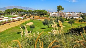 Um campo de golfe com um hotel ao fundo.
