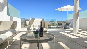 Terraço no telhado com mesa, cadeiras e uma garrafa de champanhe.