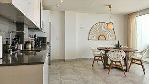 Uma cozinha moderna com uma ilha central, uma área de jantar com mesa redonda e cadeiras, e um enfeite decorativo na parede.