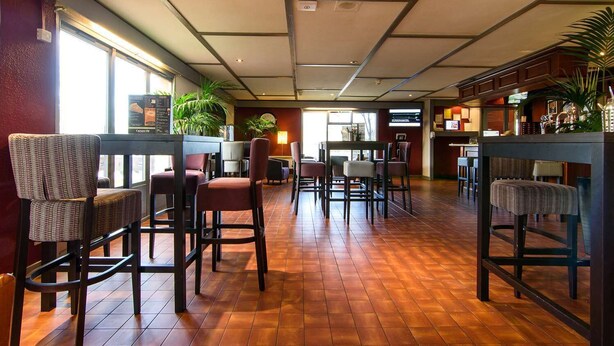 A restaurant with a wooden floor, multiple tables and chairs, and large windows allowing natural light. - The Runmere Hotel, Liverpool South (Runcorn), Part of the AG Collection (Runcorn)