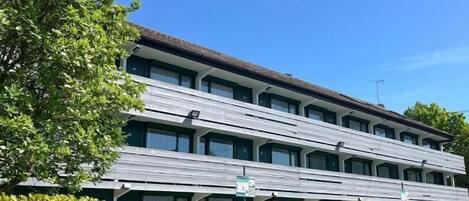 Un hotel de varios pisos con techo plano y una hilera de ventanas en cada nivel.