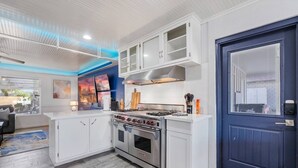 A modern kitchen with white cabinetry, a Wolf stove, and a blue door. - Heated Pool | Putting Green | 7 Min Old Town (Scottsdale)