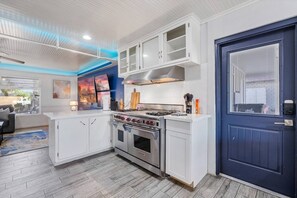 A modern kitchen with white cabinetry, a Wolf stove, and a blue door. - Heated Pool | Putting Green | 7 Min Old Town (Scottsdale)