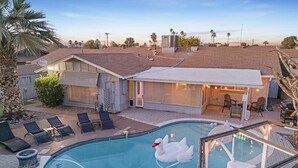 A swimming pool with a swan float, lounge chairs, and a covered patio area. - Heated Pool | Putting Green | 7 Min Old Town (Scottsdale)
