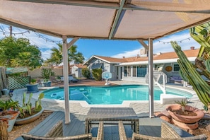 Ein Garten mit Swimmingpool, überdachter Terrasse und diversen Kübelpflanzen.
