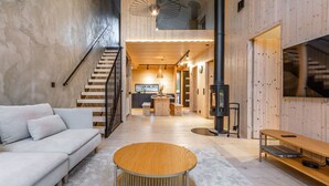 Un intérieur moderne avec un escalier en bois, une table ronde en bois et un canapé.