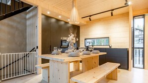 Une cuisine moderne avec des meubles en bois, un îlot central doté de sièges et un luminaire suspendu.