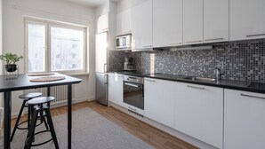 A modern kitchen with white cabinets, a black countertop, and a tiled backsplash. - Bright & Cozy 1BR Home near Downtown (Lahti)