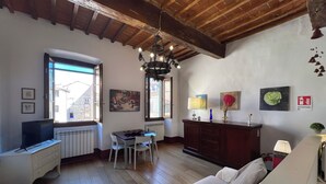 Un accogliente soggiorno con soffitto in legno, un divano, un tavolo da pranzo con sedie, una televisione e opere d'arte alle pareti.