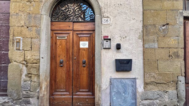 Una porta in legno doppia con un arco decorativo in metallo, con il numero 38, e una piccola cassetta delle lettere a parete.