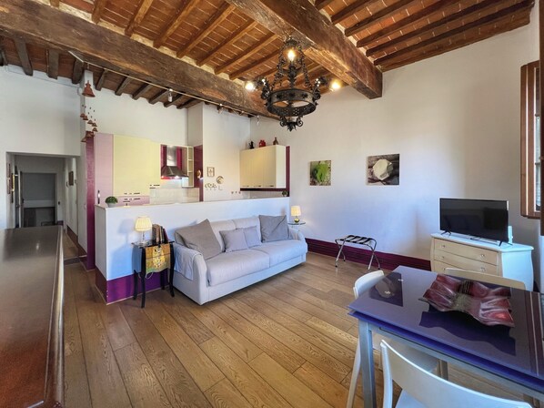 Una sala de estar acogedora con sofá, televisión y comedor con mesa y sillas.