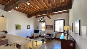 Un'ampia cucina con travi in legno, un'area pranzo con tavolo e sedie, e una vista dalla finestra.