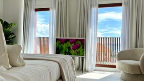 Quarto com cama, televisão e varanda com vista.