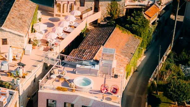 A rooftop terrace with a swimming pool, sun loungers, and a stone building with arched windows. - Aldea Calma (Sanxenxo)