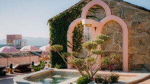 A rooftop pool area with a stone wall, a water feature, and lounge chairs. - Aldea Calma (Sanxenxo)